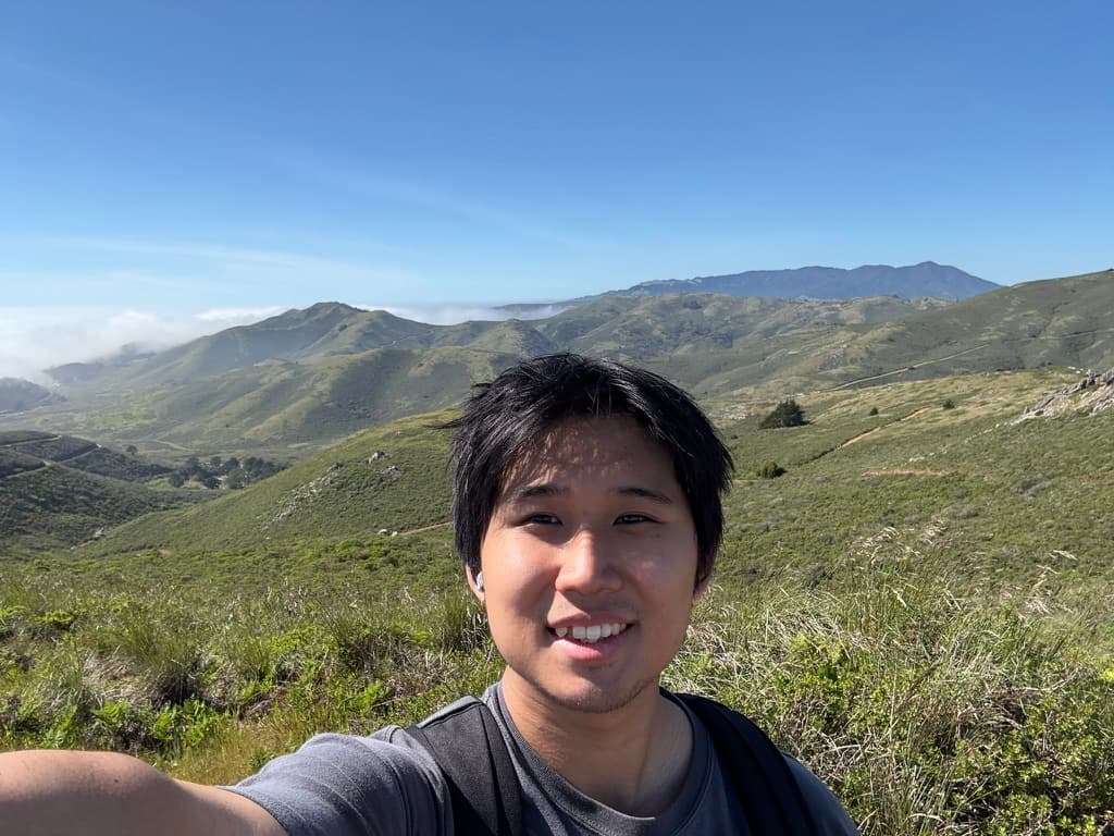 Jason smiling in front of green rolling hills