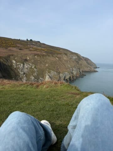Jason’s legs stretched out on a cliff above the ocean