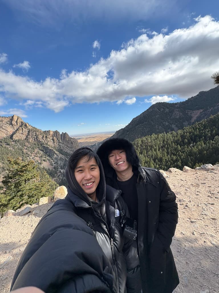 Jason and a friend taking a selfie in front of rocky mountains