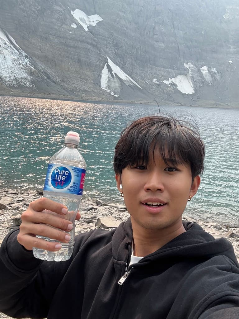 Jason holding a water bottle by a glacier lake