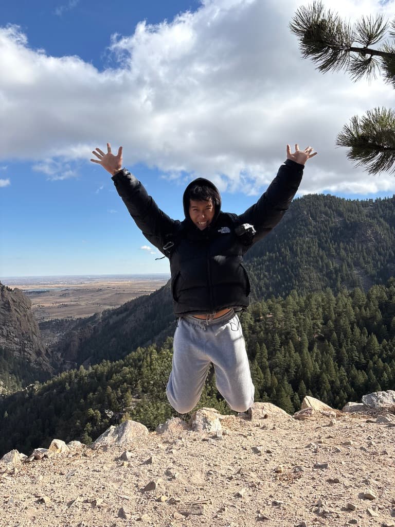 Jason jumping with his arms up on a mountain overlook