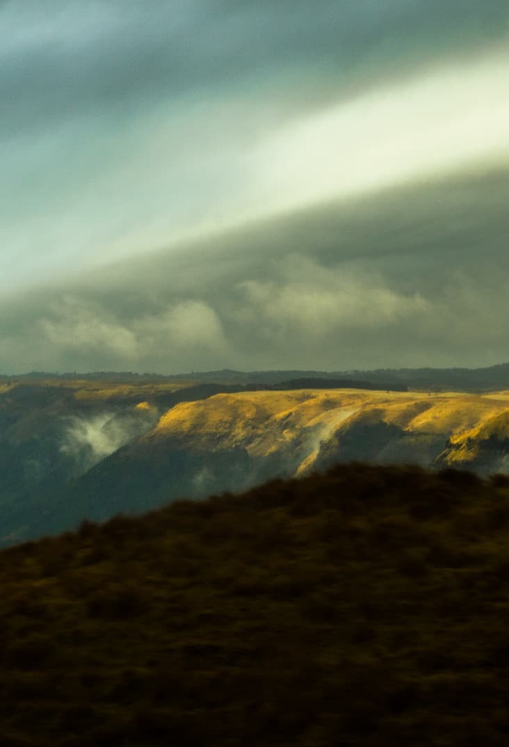 Storm clouds breaking over golden hills