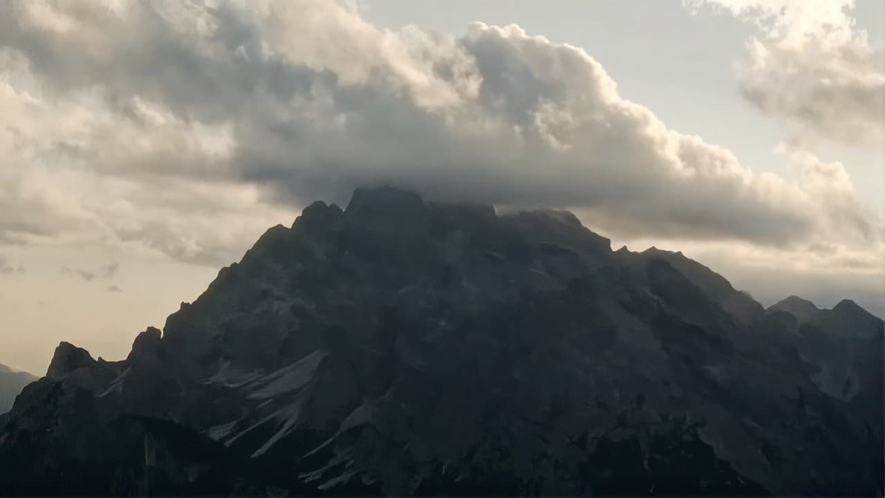 A dark mountain peak wrapped in clouds at dusk