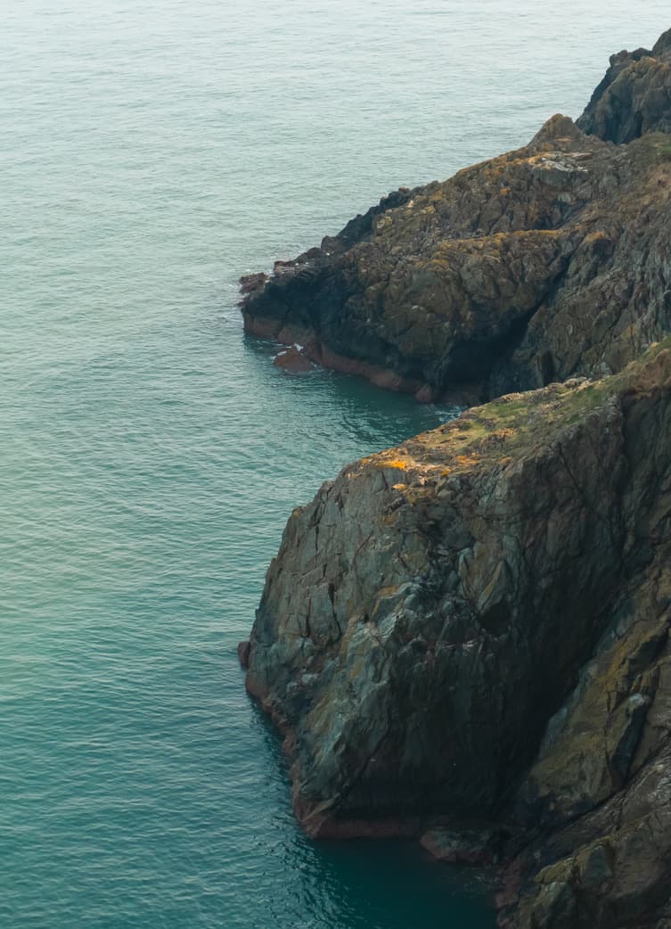Sea cliffs dropping into turquoise water, from above